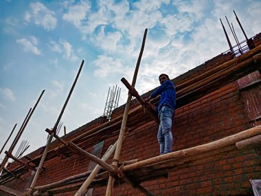 DISTRICT KATNI, Hindistan - 18 HAZİRAN 2020: Doğal gökyüzü arka planındaki inşaat alanında bambu yapısını birbirine bağlayan bir Hint köyü işçiliği.