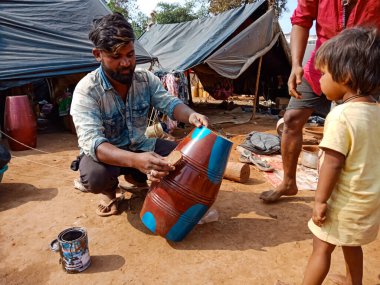 DISTRICT KATNI, INDIA - 21 HAZİRAN 2020: Açık alan atölyesinde çocukların etrafında müzik davulu çalan Hintli fakir sanatçı.