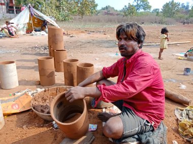 DISTRICT KATNI, INDIA - 21 HAZİRAN 2020: Hintli fakir köylü sanatçı açık alandaki orman atölyesinde toprak müzikal davul üssü uyguluyor.