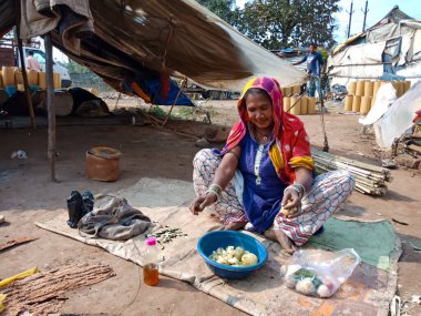 DISTRICT KATNI, INDIA - 21 HAZİRAN 2020: Açık alan atölyesinde sebze doğrayan Hintli fakir kadın.