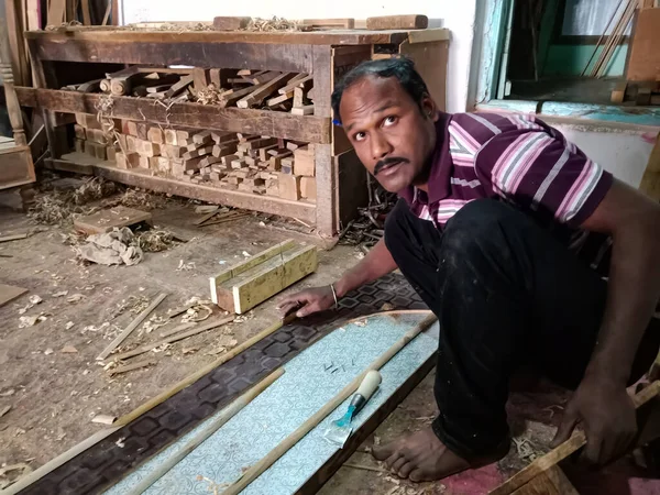 DISTRICT KATNI, INDIA - HAZİRAN 08, 2020: Bir Hintli ahşap sanatçı atölyede mobilya yaparken kameraya bakıyor.