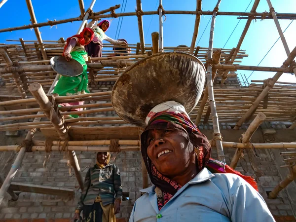 DISTRICT KATNI, INDIA - 18 HAZİRAN 2020: Bir Hint köyü kadın işçisinin kafasında gökyüzü arka planındaki inşaat sahasında güçlendirilmiş malzeme vardı.