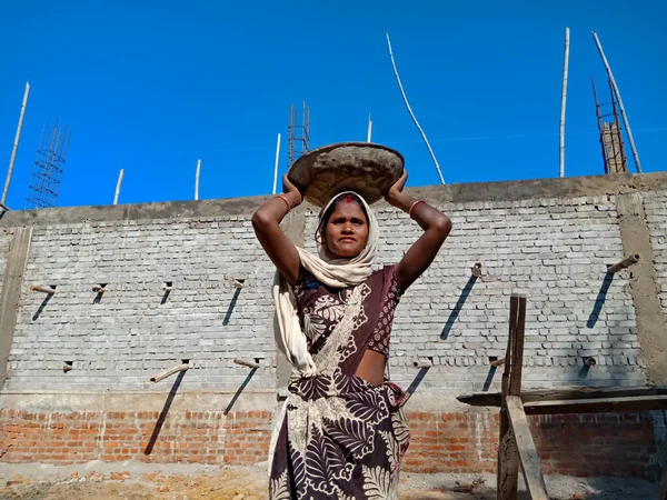 DISTRICT KATNI, INDIA - 18 HAZİRAN 2020: Hindistanlı bir işçi kadın gökyüzü arka planındaki inşaat alanında kafasına çimento kapağı taşıyor.