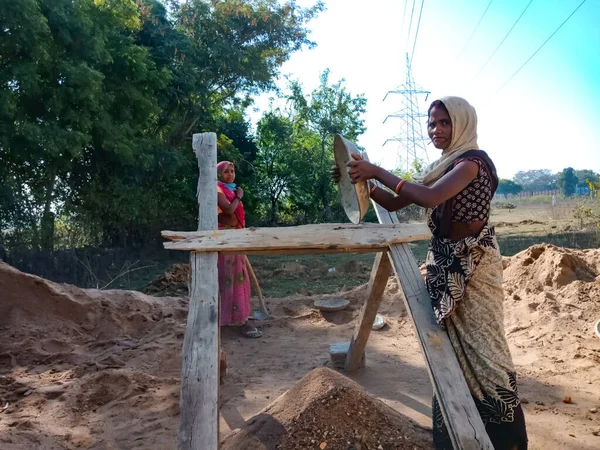 DISTRICT KATNI, INDIA - 18 Ocak 2020: Gökyüzü arka planındaki inşaat alanında kum filtreleyen Asyalı bir köylü kadın işçi.
