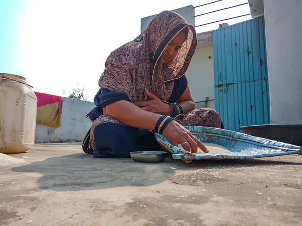 DİSTRİK KATNI, Hindistan - 18 HAZİRAN 2020: Hint köylü bir kadın pirinç tohumlarını doğal arka planda temizliyor.