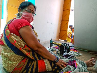 DISTRICT KATNI, INDIA - 21 Mayıs 2020: Koronavirüs koruması için yüz maskesi takan bir Hintli kadın dikiş makinesi..