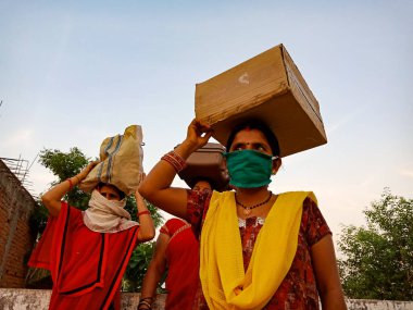 DISTRICT KATNI, INDIA - 21 Mayıs 2020: Corona virüsü koruması için yüz maskesi takan bir grup Hindistan köylü kadın gökyüzü arka planında başlarının üzerinde durdular.