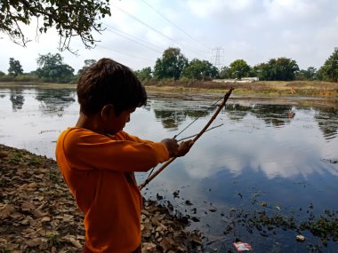 DISTRICT KATNI, INDIA - 01 Ocak 2020: Nehir kıyısındaki su gölüne ok atan Asyalı bir köy çocuğu.