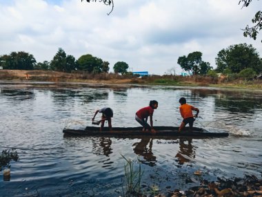 DİSTRİK KATNI, INDIA - HAZİRAN 01, 2020: Asyalı köy balıkçıları akşam vakti su gölünde kayıkla geziyorlar.