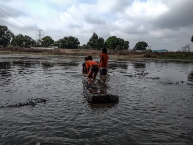 DİSTRİK KATNI, INDIA - HAZİRAN 01, 2020: Asyalı köy balıkçıları akşam vakti su gölünde kayıkla geziyorlar.