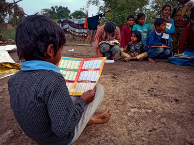 DİSTRİK KATNI, Hindistan - HAZİRAN 01, 2020: DİSTRİK KATNI, INDIA - HAZİRAN 01, 2020: Köyün açık havasında sayısal kitap okuyan Hintli bir okul çocuğu.