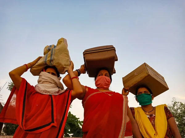 DISTRICT KATNI, INDIA - 21 Mayıs 2020: Corona virüsü koruması için yüz maskesi takan bir grup Hindistan köylü kadın gökyüzü arka planında başlarının üzerinde durdular.