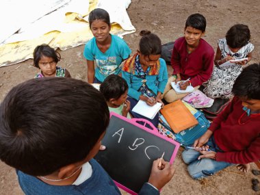 DISTRICT KATNI, INDIA - HAZİRAN 01, 2020: Asyalı fakir çiftçi çocuk açık toprak arka planında köy eğitimi sırasında ABC 'yi birlikte öğreniyor.
