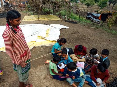 DISTRICT KATNI, INDIA - HAZİRAN 01, 2020: Köy eğitim bilinçlendirme programı sırasında açık toprak arka planında Asyalı fakir kız birlikte ders veriyor.