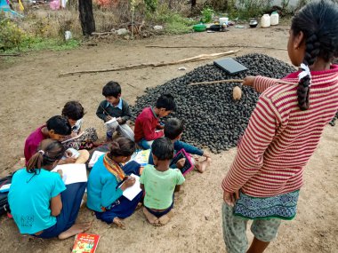 DISTRICT KATNI, INDIA - HAZİRAN 01, 2020: Asyalı yoksul çiftçi çocuklar köy eğitimi sırasında açık toprak arka planında birlikte öğreniyorlar.