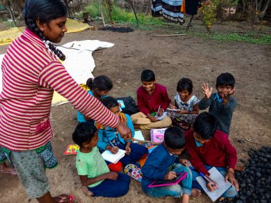 DISTRICT KATNI, INDIA - HAZİRAN 01, 2020: Asyalı yoksul çiftçi çocuklar köy eğitimi sırasında açık toprak arka planında birlikte öğreniyorlar.