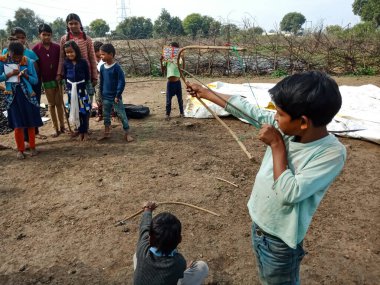DISTRICT KATNI, INDIA - HAZİRAN 01, 2020: Asyalı fakir köy çocukları taze ve sağlıklı kırsal çevrede ok atma oyunu oynuyorlar.