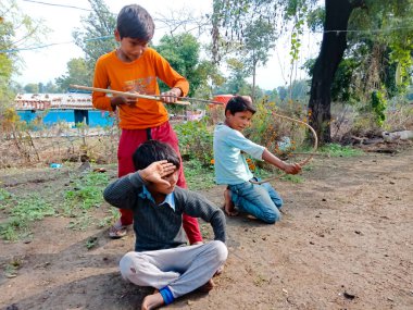 DISTRICT KATNI, INDIA - HAZİRAN 01, 2020: Asyalı fakir köy çocukları taze ve sağlıklı kırsal çevrede ok atma oyunu oynuyorlar.