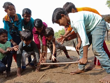 DISTRICT KATNI, INDIA - HAZİRAN 01, 2020: Asyalı fakir köy çocukları taze ve sağlıklı kırsal çevrede gilli danda oynuyorlar.