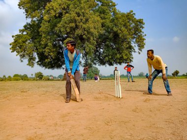 DISTRICT KATNI, INDIA - HAZİRAN 01, 2020: Kırsal alanda kriket oynayan Asyalı fakir köy çocukları grupları.