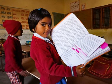 DİSTRİK KATNI, Hindistan - 13 HAZİRAN 2020: Sınıfta kırmızı renk üniforma giymiş kitap okuyan Hintli bir ilkokul öğrencisi.