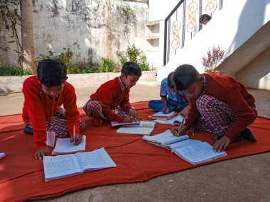 DİSTRİK KATNI, INDIA - 13 HAZİRAN 2020: Hindistan köyü çocukları açık alan avlusunda birlikte yazıyorlar.