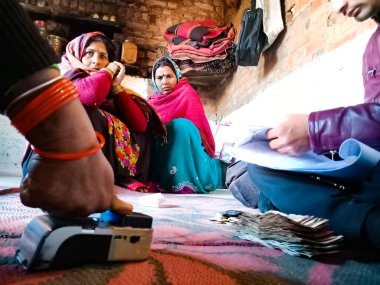 DİSTRİKT KATNI, INDIA - 16 HAZİRAN 2020: Evdeki küçük mikro finansman geri ödeme prosedürü sırasında kadın parmağı elektronik başparmak pedi makinesine dokunuyor.