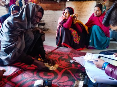DISTRICT KATNI, INDIA - 16 HAZİRAN 2020: Hindistan köyünden yaşlı bir adam evdeki küçük mikro finans kredi geri ödeme prosedürü sırasında banka memuruna para veriyor.