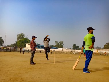 DİSTRİK KATNI, INDIA - 02 Aralık 2019: Hintli şehir çocukları güzel gökyüzü sahası etrafında birlikte kriket oynuyorlar.
