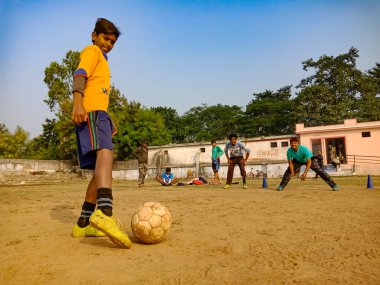 DISTRICT KATNI, INDIA - 02 Aralık 2019: Hintli şehir çocuğu güzel gökyüzü sahasının etrafındaki parkta futbol maçı için çekim yapıyor.