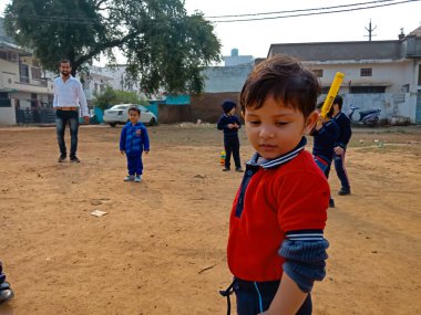 DISTRICT KATNI, INDIA - 17 HAZİRAN 2020: Hint anaokulu öğrencileri kriket maçında spor sahasında tek başlarına duruyorlar.