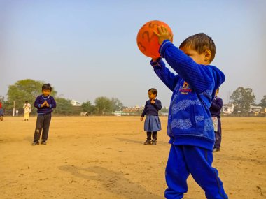 DISTRICT KATNI, INDIA - 17 HAZİRAN 2020: Hintli anaokulu erkek çocuğu voleybol maçı için voleybol topu atıyor.
