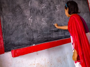 DISTRICT KATNI, INDIA - 21 HAZİRAN 2020: Hindistan devlet okulu öğrencisi sınıftaki tahtaya numara yazıyor.