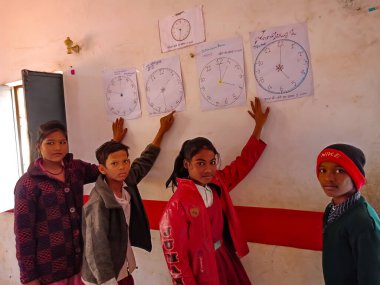 DISTRICT KATNI, INDIA - 21 HAZİRAN 2020: Hindistan devlet okulu öğrencileri grubu sınıfın duvarında saat bilimi modelini sunuyor.