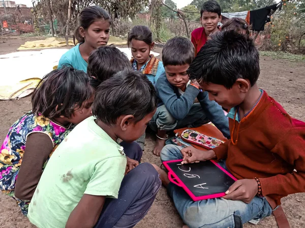 DISTRICT KATNI, INDIA - HAZİRAN 01, 2020: Asyalı yoksul çiftçi çocuklar köy eğitimi sırasında açık toprak arka planında birlikte öğreniyorlar.