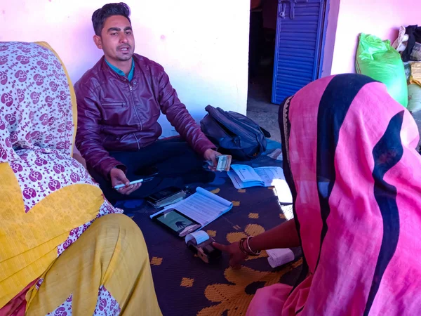 DISTRICT KATNI, INDIA - 16 HAZİRAN 2020: Hindistan köyünden bir kadın evdeki küçük mikro finansman kredi geri ödeme prosedürü sırasında parmak elektronik başparmak pedi makinesine dokunuyor.