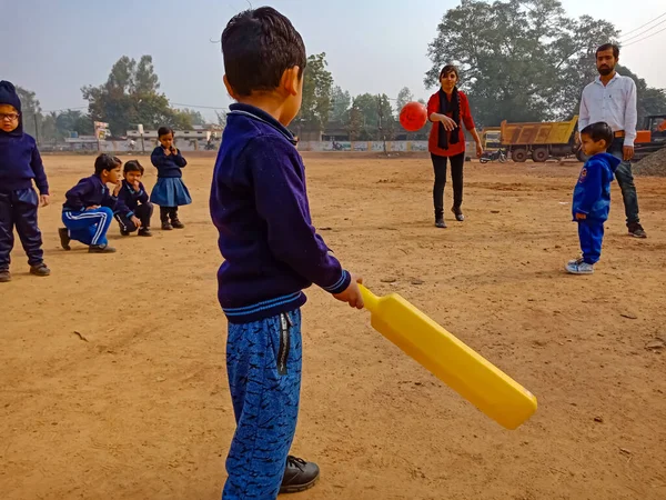 DISTRICT KATNI, INDIA - 17 HAZİRAN 2020: Hintli anaokulu çocuğu kriket oynarken beyzbol sopasını spor sahasında tutuyordu.