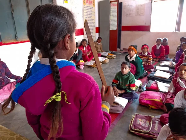 DISTRICT KATNI, INDIA - 21 HAZİRAN 2020: Hint devlet okulunda ders verirken elinde ahşap çubuk tutan kız öğrenci.