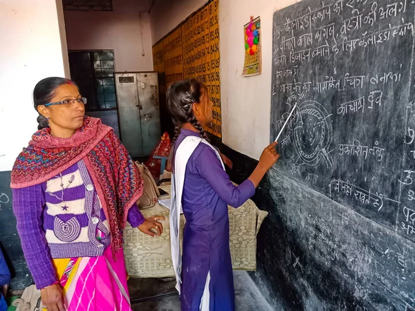 DISTRICT KATNI, INDIA - 21 HAZİRAN 2020: Sınıfta okurken kız öğrenciyi destekleyen Hint devlet okulu öğretmeni.