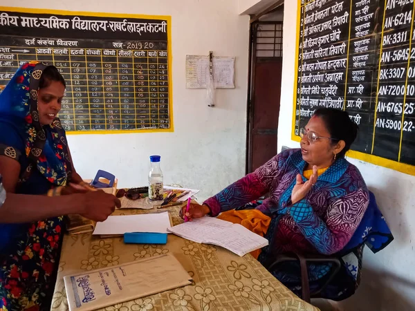 DISTRICT KATNI, INDIA - 21 HAZİRAN 2020: Hindistan devlet okulu müdürü ofis masasında köy velileriyle konuşuyor.