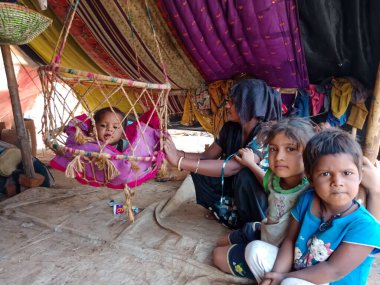 DİSTRİK KATNI, INDIA - 29 HAZİRAN 2020: Fakir bir Asyalı anne yeni doğan çocuğunu salıncakta sallıyor.