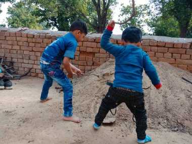 DİSTRİK BILASPUR, Hindistan - 25 Şubat 2020: Gökyüzü arka planında toprak alanda birlikte oynayan iki küçük Hintli çocuk.