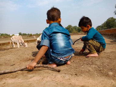 DİSTRİK BILASPUR, Hindistan - 25 Şubat 2020: Gökyüzü arka planında toprak alanında birlikte oynayan iki küçük Hintli çocuk.
