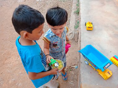 DISTRICT KATNI, INDIA - 21 Mayıs 2020: İki Hintli küçük şirin çocuk açık ortamda oyuncak arabayla birlikte oynuyorlar.