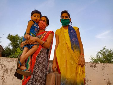 DISTRICT KATNI, INDIA - 21 Mayıs 2020: Hintli anne, Corona virüsü koruması için maske takarken sevimli bebeğini kucağında taşıdı.