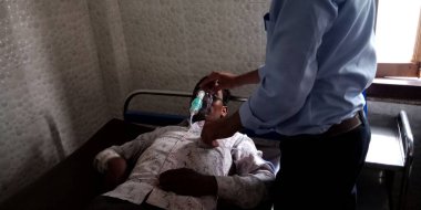 DISTRICT KATNI, Hindistan - 28 Eylül 2019: Bir Hintli erkek hemşire hastane koğuşundaki hasta ağzına oksijen maskesi takıyor.