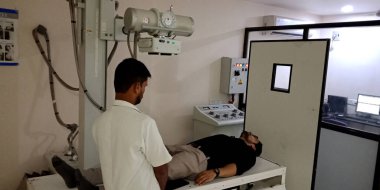 DİSTRİK KATNI, Hindistan - 28 Eylül 2019: Asyalı bir laboratuvar teknisyeni kemik kırığı hastanesinde erkek bacağının röntgenini çekiyor.