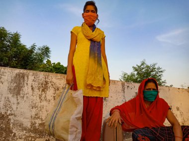 DISTRICT KATNI, INDIA - 21 Mayıs 2020: Koronavirüs koruması için maske takan fakir bir Hint köyü anne ve kızı.