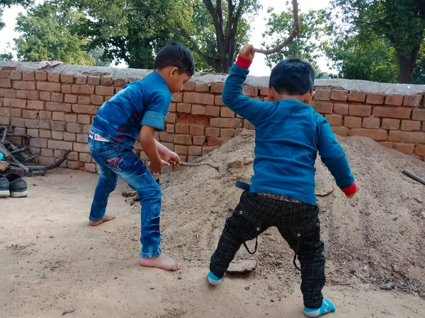 DİSTRİK BILASPUR, Hindistan - 25 Şubat 2020: Gökyüzü arka planında toprak alanda birlikte oynayan iki küçük Hintli çocuk.