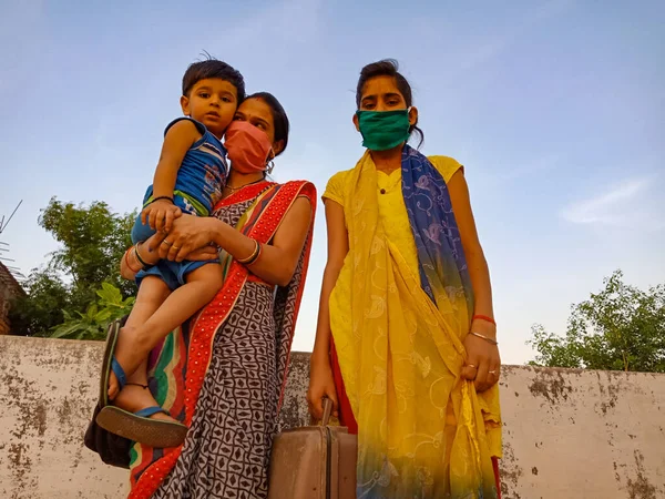 DISTRICT KATNI, INDIA - 21 Mayıs 2020: Hintli anne, Corona virüsü koruması için maske takarken sevimli bebeğini kucağında taşıdı.